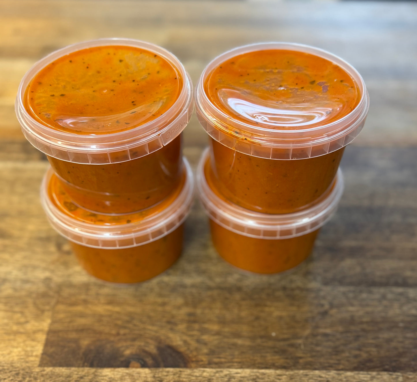 Single Serve Creamy Tomato Soup – 4 Pack in clear containers on a wooden surface, rich and comforting.