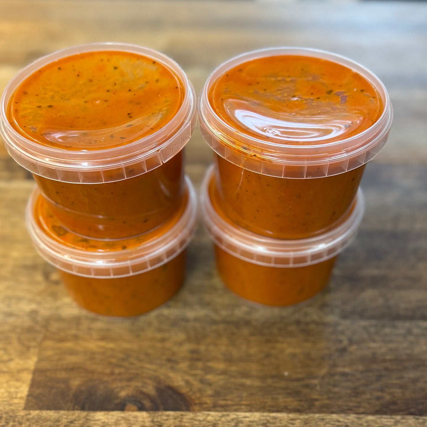 Single Serve Creamy Tomato Soup – 4 Pack in clear containers on a wooden surface, rich and comforting.