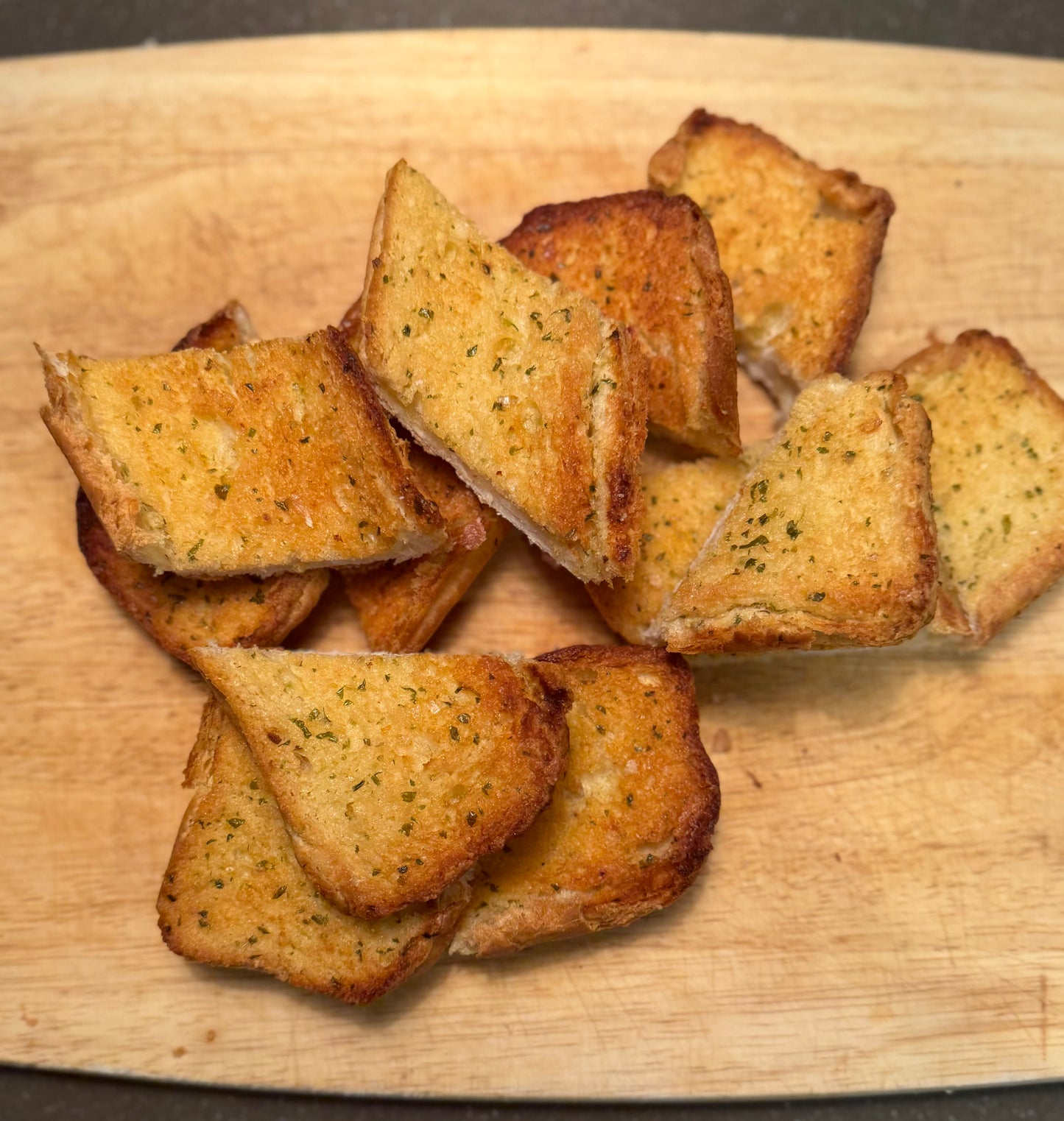 Twin Pack of Garlic Bread pieces on a wooden cutting board, crispy and golden brown.