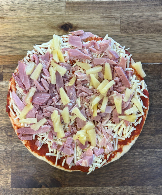 Ham and Pineapple Pizza topped with shredded ham and pineapple on a crust, ready for baking.