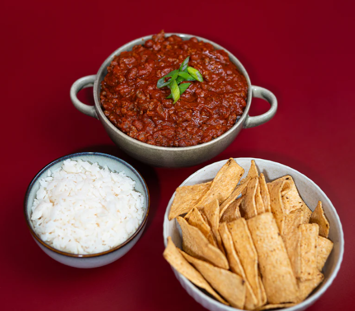 Delicious bowl of Lane's Hearty Classic Chilli Recipe Base with rice and crispy tortilla chips.