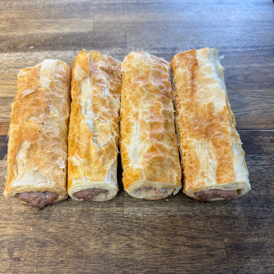 Four sausage rolls on a wooden surface