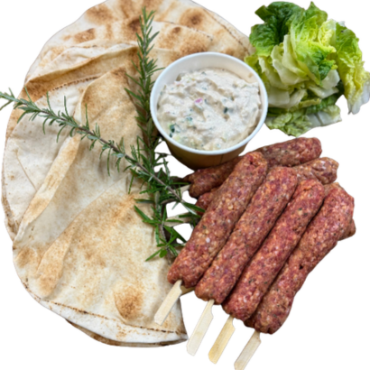 Platter with sliced bread, skewered meats, and a small bowl of sauce on a white background